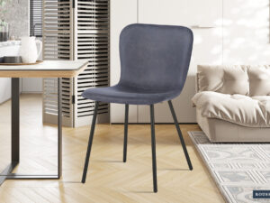Een moderne kamer met Stoel 'Susan' PU Donkergrijs stoelen (2 per doos) met zwarte metalen poten, geplaatst op een lichte houten visgraatvloer naast een beige bank, een kleine eettafel en een witte kast.