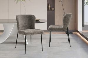 Twee Stoel 'Lisa' Bouclé Zand stoelen (set van 2) met een modern design staan in een chique eetkamer, gecombineerd met een witte tafel en een modern interieur tegen neutrale muren.