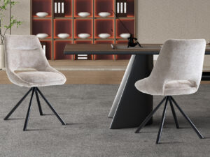 Twee Stoel 'Dante' Stof Beige stoelen (2 per doos) met zwarte metalen poten staan bij een strakke tafel op grijs tapijt. Op de achtergrond staan planken met witte kommen en boeken, plus een klein plantje ter decoratie.
