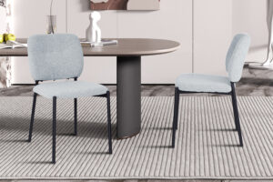 Twee PROMO - Stoel 'Sophia' Stof Lichtgrijs stoelen staan op een gestreept vloerkleed bij een ronde tafel met een zwart onderstel en creëren een stijlvol, eigentijds interieur.