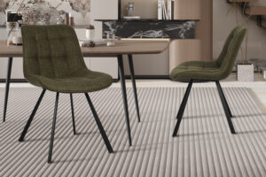 Twee Stoel 'Ariba' Stof Ote Montego 350 Groen stoelen met zwarte metalen poten staan rond een houten eettafel op een geribbeld lichtgrijs vloerkleed in een stijlvolle, eigentijdse kamer met neutrale tinten en decoratieve accenten.