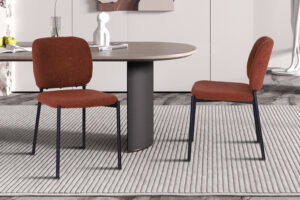Twee PROMO 'Sophia' stoelen in roestkleurige stof met zwarte metalen poten staan rond een ronde tafel met een grijs cilindrisch onderstel op een lichtgestreept vloerkleed, waardoor een eigentijdse kameropstelling ontstaat.