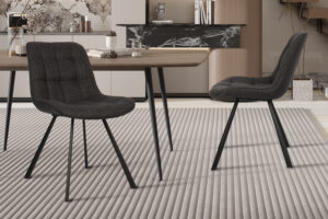 Twee Stoel 'Ariba' stoelen in Ote Montego 460 donkergrijze stof (set van 2) met zwarte poten staan rond een houten eettafel op een beige vloerkleed in een moderne kamer met een minimalistische, neutrale inrichting.