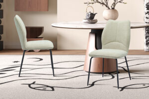 Twee ecru 'Lara' stoffen stoelen (2 per doos) staan bij een ronde tafel met een marmeren blad en licht houten onderstel, op een beige vloerkleed met zwarte abstracte motieven in een moderne eetkamer.