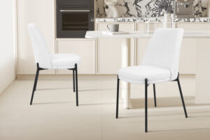 Twee SALE - Stoel 'Ella' Stof Wit stoelen (2 per doos) met zwarte poten staan in een lichte, minimalistische keuken met marmeren accenten, een ingebouwde oven en een moderne eettafel met kop en schotel.