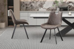 Twee Stoel 'Pablo' Micro fiber PU Donkergrijs stoelen (set van 2) met zwarte poten staan op een grijs vloerkleed met structuur in een moderne eetkamer met een marmeren accentmuur en een strakke witte tafel.