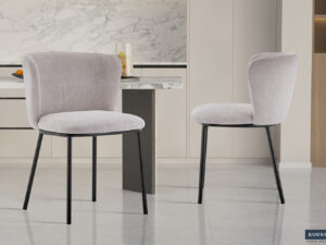 Twee Stoel 'Arthur' Stof Ote Belfast 23 Beige stoelen (set van 2) met beige bekleding en zwarte metalen poten staan in een moderne, minimalistische keuken met marmeren aanrechtblad en lichte kasten.