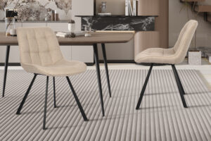 Twee Stoel 'Ariba' stoelen in beige/lichtgrijze stof staan rond een houten eettafel op een geribbeld lichtgrijs vloerkleed en creëren een moderne ruimte met neutrale tinten en een minimalistische inrichting.