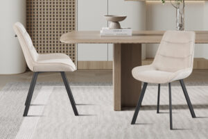 Twee Stoel 'Amelie' Corduroy Zand stoelen (set van 2) met beige bekleding en zwarte poten staan rond een houten eettafel in een stijlvolle, neutrale kamer met minimalistische inrichting en een licht vloerkleed.