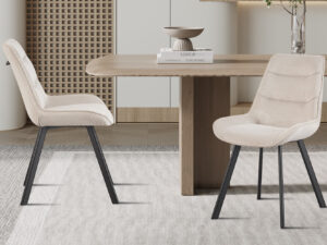 Twee Stoelen van Amelie Corduroy Zand stoelen (set van 2) met beige bekleding en zwarte poten staan rond een houten eettafel in een stijlvolle, neutrale kamer met minimalistische inrichting en een licht vloerkleed.