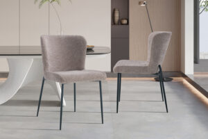 Twee Stoel 'Ariba' Stof Ote Montego 253 Rood stoelen (set van 2) geven een levendig accent aan een witte eettafel in een stijlvolle, minimalistische eetkamer met neutrale inrichting en moderne accenten.