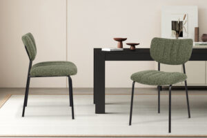 Twee Stoel 'Antura' Stof Ote Lisa 356 stoelen in groen (set van 2) met zwarte poten staan naast een zwarte rechthoekige tafel in een moderne, minimalistische kamer met neutrale muren, een wit vloerkleed en eenvoudige inrichting.