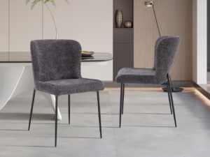 Twee Stoel 'Lisa' Bouclé Donkergrijs stoelen (2 per doos) met pluche donkergrijze stof en slanke zwarte metalen poten verfraaien een minimalistische eetkamer, in combinatie met een sculpturale witte tafel en decoratieve accenten op de achtergrond.