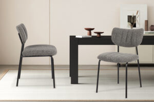 Twee Stoel 'Antura' Stof Ote Lisa 456 Donkergrijs stoelen (2 per doos) met zwarte metalen poten staan bij een moderne zwarte tafel in een minimale, stijlvolle kamer met neutrale tinten en eenvoudige inrichting.