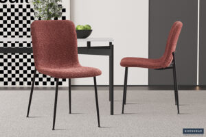 Twee Eetkamerstoel 'Alice' Bouclé Roze stoelen staan rond een witte tafel met groene appels. De kamer heeft een grijs tapijt en abstracte muurkunst op de achtergrond.