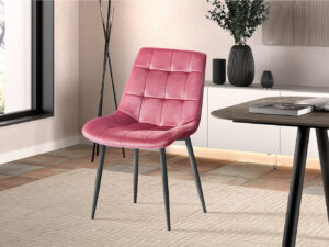 Een moderne kamer met Stoel 'Juta' Fluweel Roze stoelen (2 per doos) met zwarte poten, op een vloerkleed met een licht patroon. Een raam, een tegelvloer en een dressoir versierd met vazen en boeken maken de achtergrond compleet.
