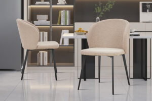 Twee Stoel 'Toledo' Bouclé Zand stoelen (set van 2) met zwarte metalen poten staan in een moderne keuken, aangevuld met ingebouwde planken, boeken, decor, een fruittoonbank en strakke eigentijdse details.