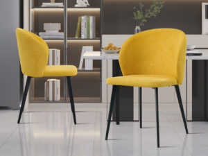Twee gele stoffen 'Toledo'-stoelen (set van 2) met zwarte poten fleuren een keuken op met een wit aanrecht, een fruitschaal, planken met boeken en decor en een lichtgrijze tegelvloer.