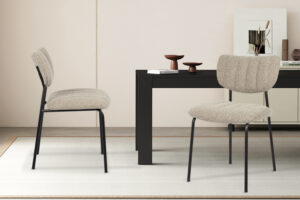 Twee 'Antura' Ote Lisa 170 stoffen stoelen (set van 2) staan bij een zwarte rechthoekige tafel in een minimalistische kamer met lichte muren, een vloerkleed en eenvoudige decoraties en kunstwerken op de achtergrond.