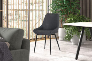 Een moderne woonkamer met PROMO - Stoel 'Mirano' PU Donkergrijs fauteuils, een ronde lichte tafel en groene potplanten bij grote ramen met verticale houten jaloezieën.