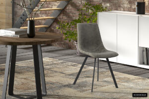 Een modern interieur met de Stoel 'Oslo' PU Grijs stoel, een ronde houten tafel met een vaas, een vloerkleed met patroon, een witte kast en een bakstenen muur met een trap en groene planten op de achtergrond.