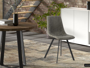Een modern interieur met de Stoel 'Oslo' PU Grijs stoel, een ronde houten tafel met een vaas, een vloerkleed met patroon, een witte kast en een bakstenen muur met een trap en groene planten op de achtergrond.