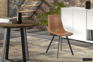 Een moderne woonruimte met de Stoel 'Oslo' PU Cognac stoelen, een ronde houten tafel, vloerkleed met licht patroon, witte buffetkast, groene plant en een muur van zichtbare bakstenen met een stalen trap op de achtergrond.
