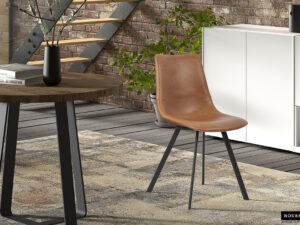 Een moderne woonruimte met de Stoel 'Oslo' PU Cognac stoelen, een ronde houten tafel, vloerkleed met licht patroon, witte buffetkast, groene plant en een muur van zichtbare bakstenen met een stalen trap op de achtergrond.