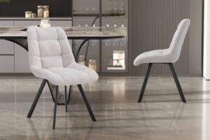 Twee 'Lizzy' stoelen in Ote Share 101 beige stof, verkocht als set van 2, hebben zwarte metalen poten en zijn geplaatst in een hedendaagse keuken met een marmeren tafel, glazen kasten en een gepolijste stenen vloer.