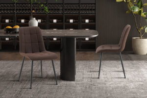 Een moderne eethoek met een ronde zwarte tafel, vier 'Furas' PU donkerbruin stoelen, een grijs vloerkleed met structuur, donkere planken vol wijnflessen op de achtergrond en een potplant rechts.