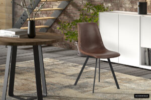 Een moderne woonruimte met de Stoel 'Oslo' PU Bruin stoel met zwarte poten op een gedessineerd vloerkleed, naast een ronde houten tafel met een vaas, een witte kast en een zichtbare bakstenen muur bij de trap.
