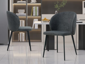 Twee Stoel 'Toledo' Stof Donkergrijs stoelen (set van 2) met zwarte metalen poten staan in een strakke keuken met een marmeren vloer, lichte kasten, een tafel met fruit en planken vol boeken en decor.