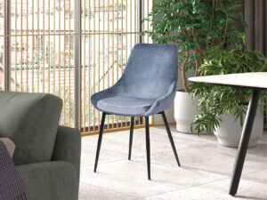 Een moderne woonkamer met Stoel 'Mirano' Fluweel Blauw accentstoelen op zwarte poten, geplaatst bij een ronde tafel en groene planten in potten. Hoge ramen met verticale jaloezieën vullen de ruimte met natuurlijk licht.
