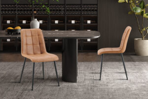 Moderne eethoek met vier 'Furas' Vintage PU Cognac stoelen rond een zwarte ovalen tafel op een tapijt met structuur. Op de achtergrond staan wijnflessen op planken en rechts staat een grote plant.