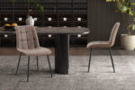 Vier vintage bruine PU 'Furas' stoelen staan rond een ronde, donker marmeren tafel, aangevuld met een vloerkleed met textuur, een grote potplant en planken met wijnflessen op de achtergrond.