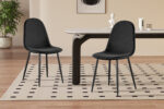 Twee Stoel 'Boy' Fluweel Zwart stoelen (set van 2) met afgeronde rugleuning staan op een crèmekleurig en zwart gestippeld vloerkleed in een stijlvolle, minimale eetkamer met een rechthoekige tafel, decoratieve accenten en een potplant op de achtergrond.