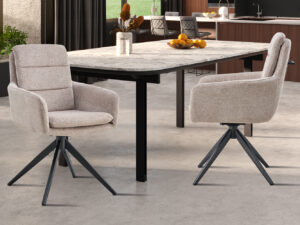 Twee Stoel 'Sevilla' Stof Beige stoelen (set van 2) met zwarte poten omringen een moderne eettafel met marmeren blad in een eigentijdse keuken. Een schaal met sinaasappels siert het tafelblad.