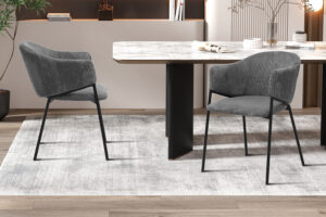 Twee Stoel 'Hugo' Corduroy Donkergrijs stoelen (set van 2) met zwarte metalen poten worden gecombineerd met een rechthoekige lichtgekleurde eettafel op een lichtgrijs vloerkleed in een moderne eetkamer.