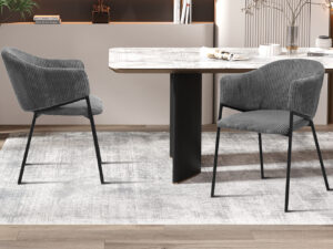 Twee Stoel 'Hugo' Corduroy Donkergrijs stoelen (set van 2) met zwarte metalen poten worden gecombineerd met een rechthoekige lichtgekleurde eettafel op een lichtgrijs vloerkleed in een moderne eetkamer.