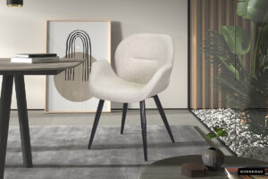 De SALE - Stoel 'Maxim' Stof Beige (2 per doos) heeft een moderne beige bekleding en zwarte poten, geplaatst op een grijs vloerkleed bij een ronde tafel, met abstracte muurkunst erachter en groene planten naast witte stenen vlakbij.