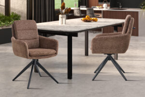 Twee Stoel 'Lisold' Draaibaar tot 0 Stof Fabb Raven 45 Bruin stoelen (set van 2) met zwart metalen poten zijn geplaatst rond een moderne marmeren eettafel in een eigentijdse keuken, gedecoreerd met een fruitschaal en accenten.