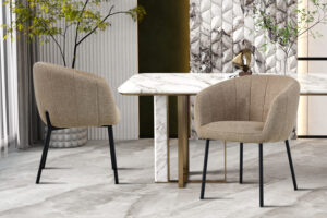 Twee Stoel 'Sevilla' Stof Zand stoelen (set van 2) met zwarte poten zijn geplaatst rond een wit marmeren eettafel met messing accenten in een moderne kamer met gestructureerde muren, planten en decoratieve sculpturen.