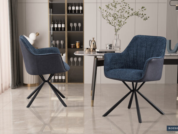 Twee SALE - Eetkamerstoel 'Lucie' Bouclé Blauw Vloerkleed PU Blauw stoelen (2 per doos) met zwart metalen poten staan in een stijlvolle eetkamer met een marmeren vloer, moderne tafel, planken met glazen en flessen en een vaas met takken.