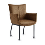Eetkamerstoel Thomas - Microleder Cognac: Cognacbruin gestoffeerde fauteuil met zwarte metalen poten en zwenkwielen, met een gebogen rugleuning, een gewatteerde zitting en licht uitlopende armleuningen, afgebeeld tegen een witte achtergrond.