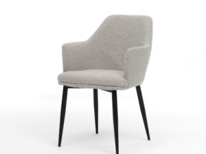 De Calvin Eetkamerstoel Stof Teddy Natural is een moderne gestoffeerde fauteuil met natuurlijke teddystof, een schuine rugleuning en slanke, zwarte metalen poten, afgebeeld tegen een effen witte achtergrond.