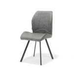 De Stoel Gana zwart Stof Soft Steel is een moderne grijze stoel met een gebogen, gewatteerde zitting en rugleuning, geaccentueerd door gestikte lijnen. Hij staat op vier slanke, naar buiten gerichte, zwarte metalen poten, die afsteken tegen een effen witte achtergrond.