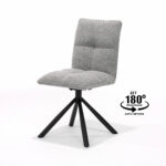 De Leon stoel MT2-Stof Alpine Steel #149 heeft een modern, grijs stoffen design met een gewatteerde, gecapitonneerde zitting en rugleuning, zwarte schuine poten en een 180° automatische terugdraaifunctie, gemarkeerd met tekst en pijlen naast de stoel.
