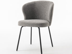 De Corsica Eetkamerstoel Stof Teddy Steel is een moderne stoel met een gebogen rugleuning, grijze structuurbekleding en vier slanke, zwarte metalen poten, afgebeeld tegen een effen witte achtergrond.