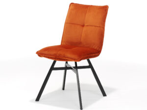 De Stoel Ramon zwart - Stof Velours Roest is een moderne stoel met een oranje fluwelen zitting en rugleuning, zwarte metalen poten, afgebeeld op een effen witte achtergrond.