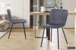 Twee Stoel 'Susan' PU Donkergrijs stoelen (2 per doos) met zwart metalen poten staan in een stijlvolle, lichte eetkamer met een houten tafel, parketvloer, lichte muren en het Rousseau logo zichtbaar in de rechter benedenhoek.